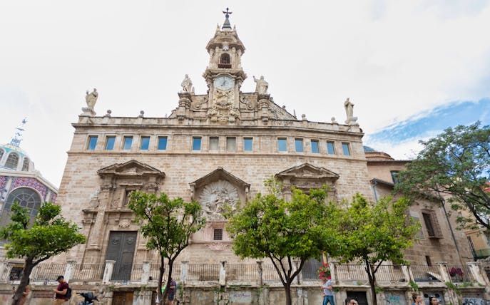 Santos Juanes Church facade with clock tower and statues in Valencia, Spain.
