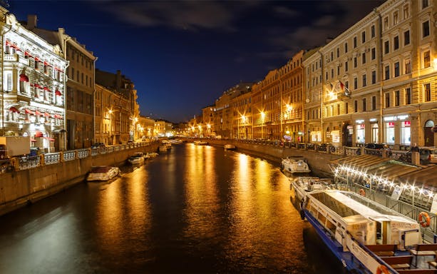 Nevsky Prospekt evening canal view with illuminated buildings and boats, St. Petersburg.