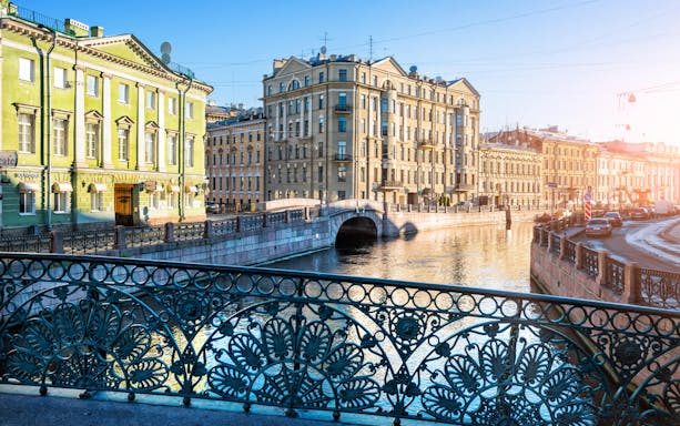Canal view with historic buildings and ornate bridge railing in St. Petersburg.