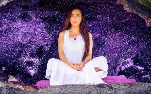 Woman meditating inside amethyst cave at Crystal Castle, Byron Bay.