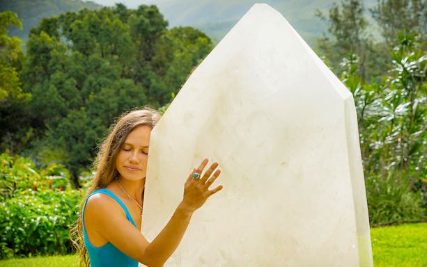 Person embracing large crystal at Crystal Castle & Shambhala Gardens, Byron Bay.