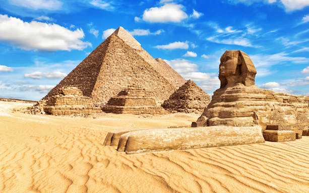 Pyramids of Giza and Sphinx under blue sky on guided tour.