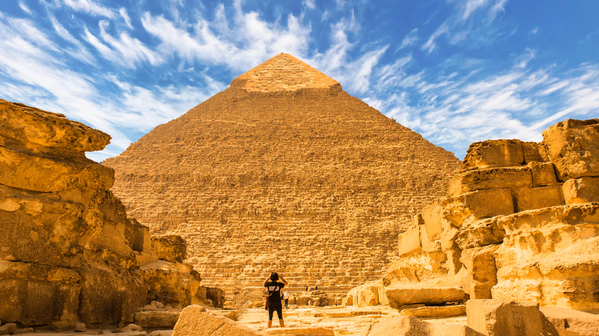 Visitor exploring the Great Pyramid of Giza on a guided tour under a clear sky.