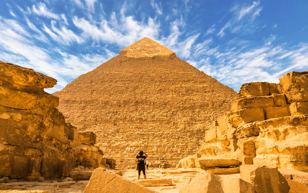 Visitor exploring the Great Pyramid of Giza on a guided tour under a clear sky.