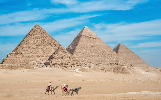 Pyramids of Giza with camel and carriage in the foreground.