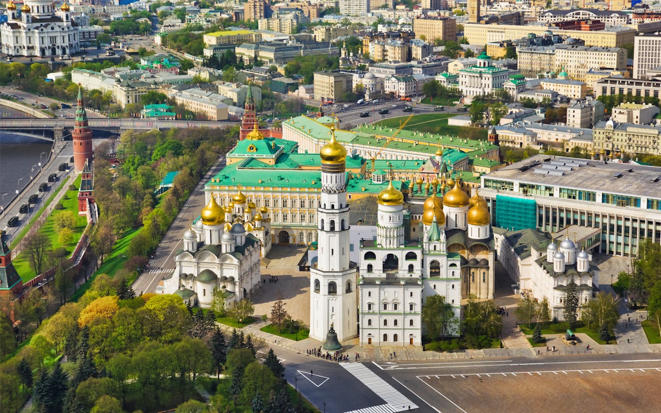 Aerial view of the Kremlin in Moscow, featuring golden domes and historic architecture.