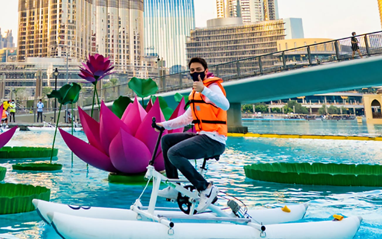 Water bike rider at Dubai Fountain with cityscape backdrop.