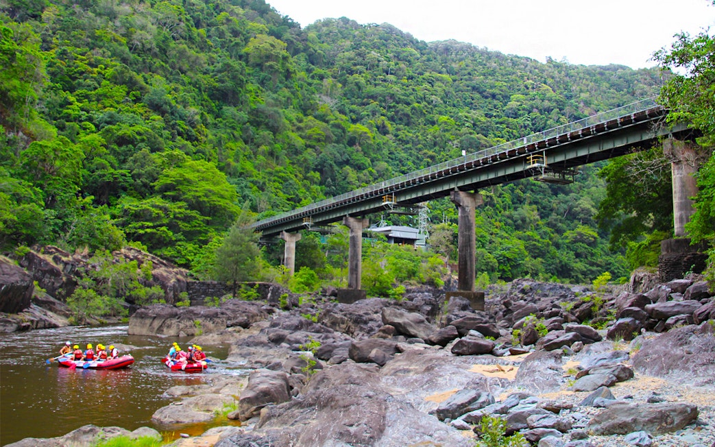 Rafting group on Barron River under a bridge surrounded by lush forest.