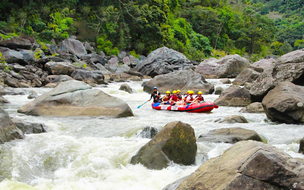 Rafting group navigating rapids on Barron River surrounded by lush forest.