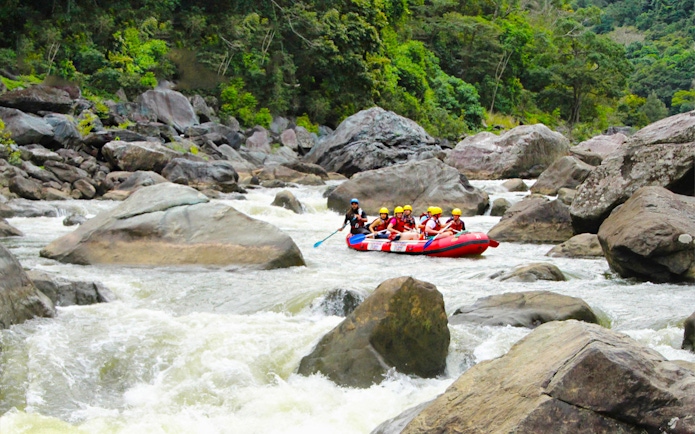 Rafting group navigating rapids on Barron River surrounded by lush forest.