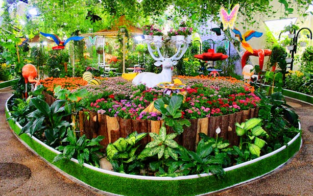 Visitors exploring vibrant flora and butterfly sculptures at Dubai Butterfly Garden.