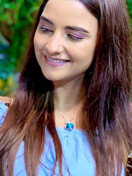 Woman smiling at a blue butterfly on her arm at Dubai Butterfly Garden.