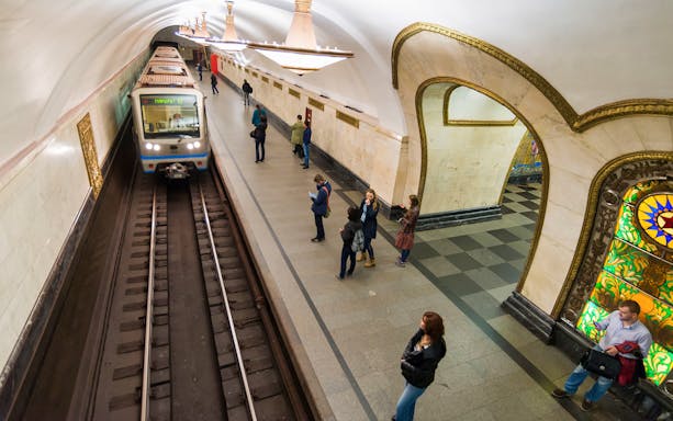 Moscow Metro station with arriving train and passengers on platform.