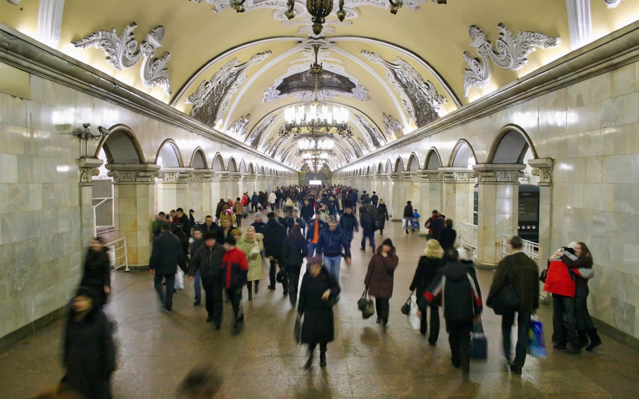 Crowded Moscow Metro station with ornate ceiling during guided tour.