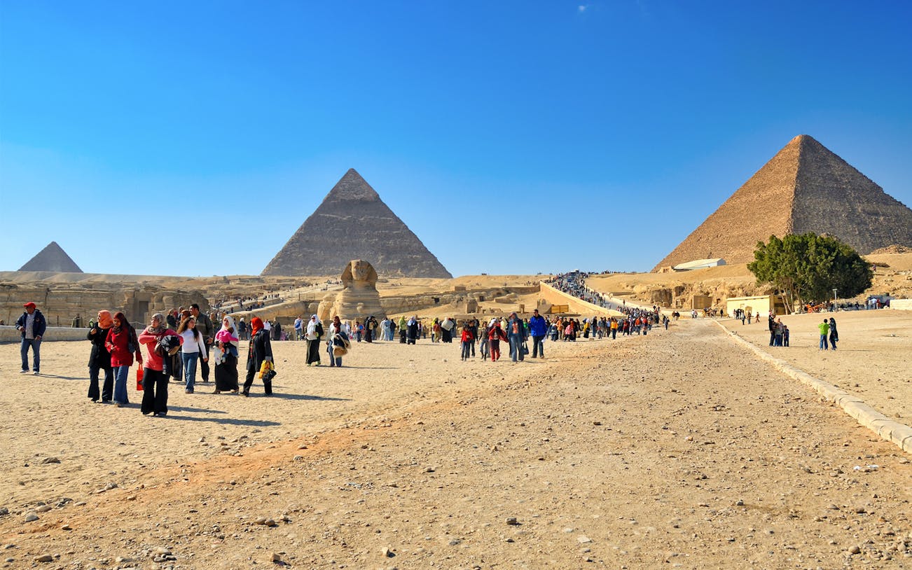 Tourists exploring the Pyramids of Giza and the Sphinx on a half-day tour in Egypt.