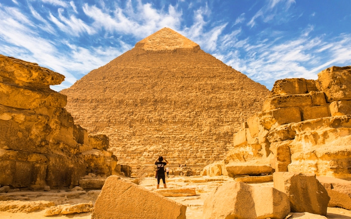 Pyramid of Giza with a person standing in front, part of a private quad and camel ride tour.