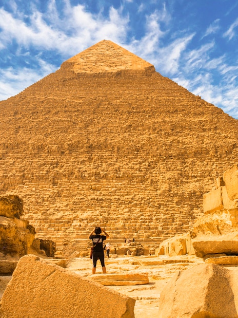 Pyramid of Giza with a person standing in front, part of a private quad and camel ride tour.