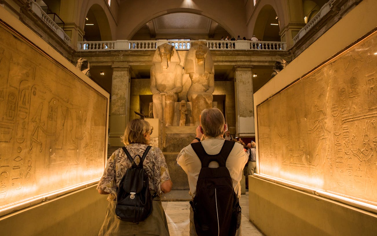 Visitors exploring ancient statues and hieroglyphs at the Egyptian Museum.