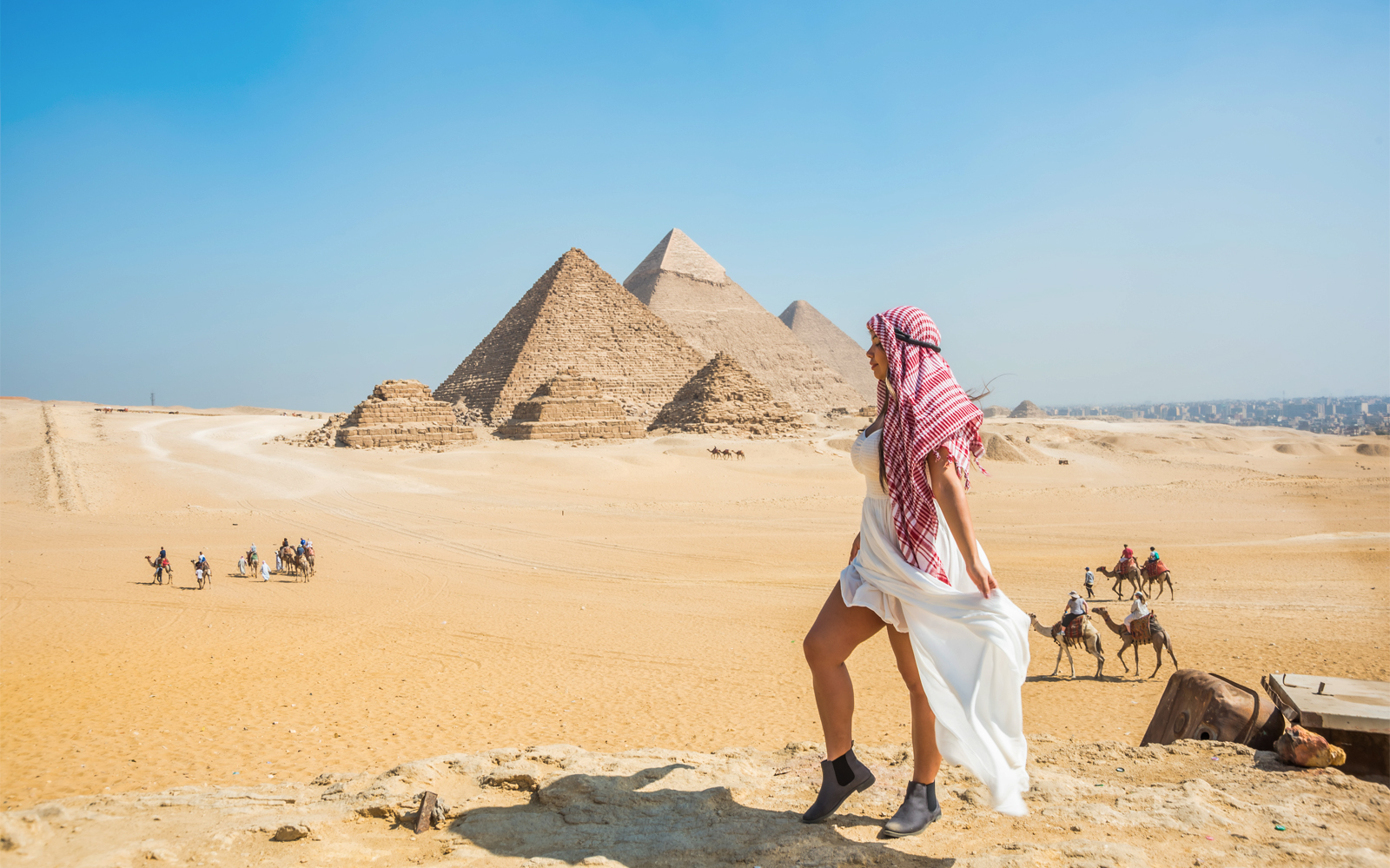 Tourist walking near the Pyramids of Giza with camels in the background, Egypt.