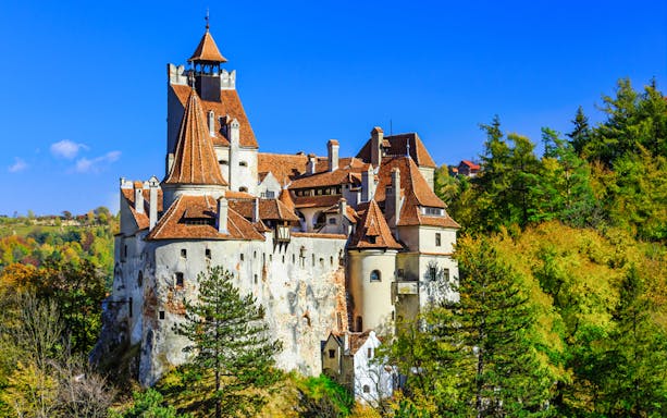 Bran Castle in Transylvania surrounded by autumn trees, part of Dracula's life journey tour.