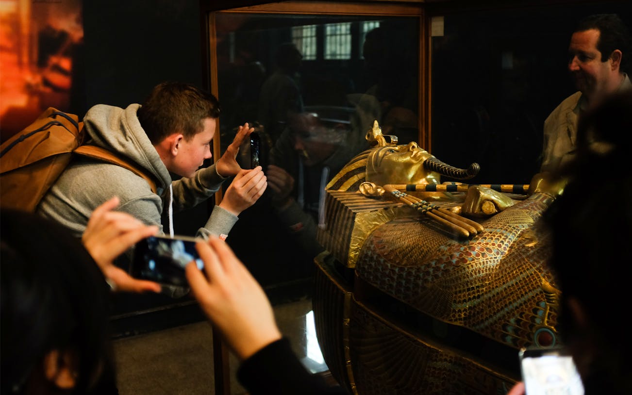 Visitors photographing a pharaoh's sarcophagus at the Egyptian Museum.
