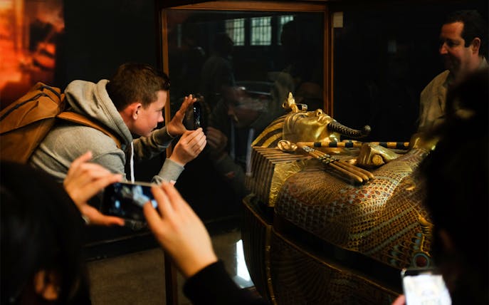 Visitors photographing a pharaoh's sarcophagus at the Egyptian Museum.
