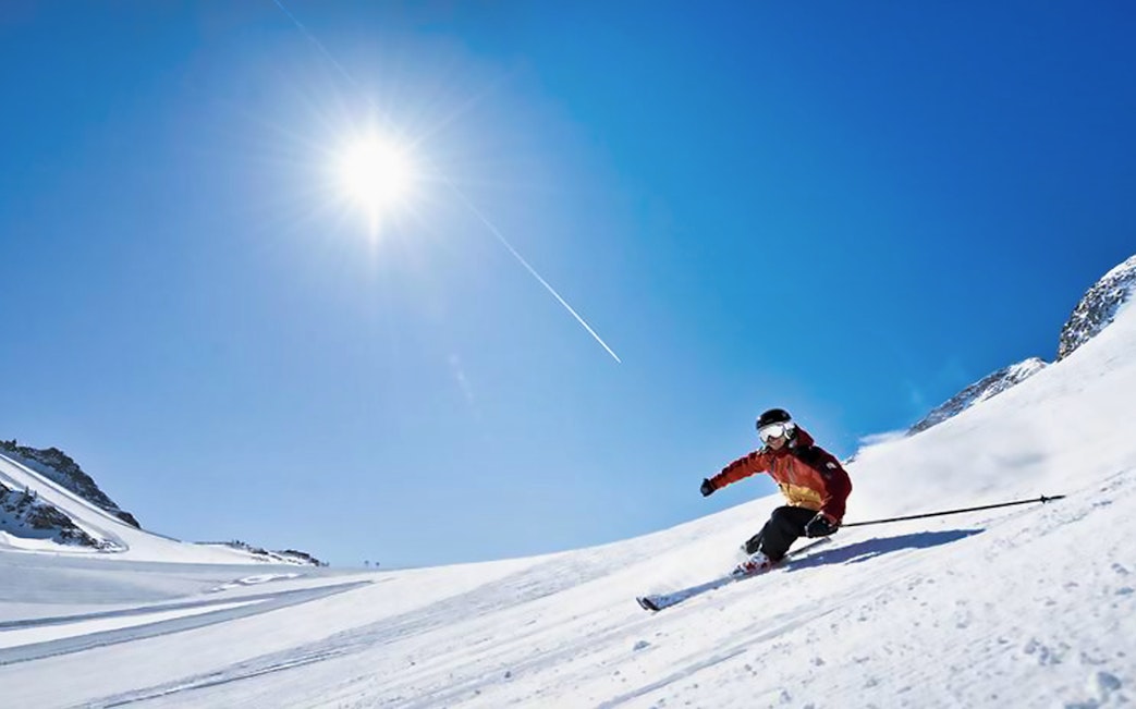 Skier on Tux Zillertaler glacier slope under clear blue sky.