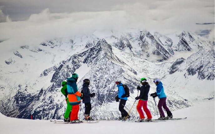 Skiers on Tux Zillertaler Glacier with snowy mountain backdrop.