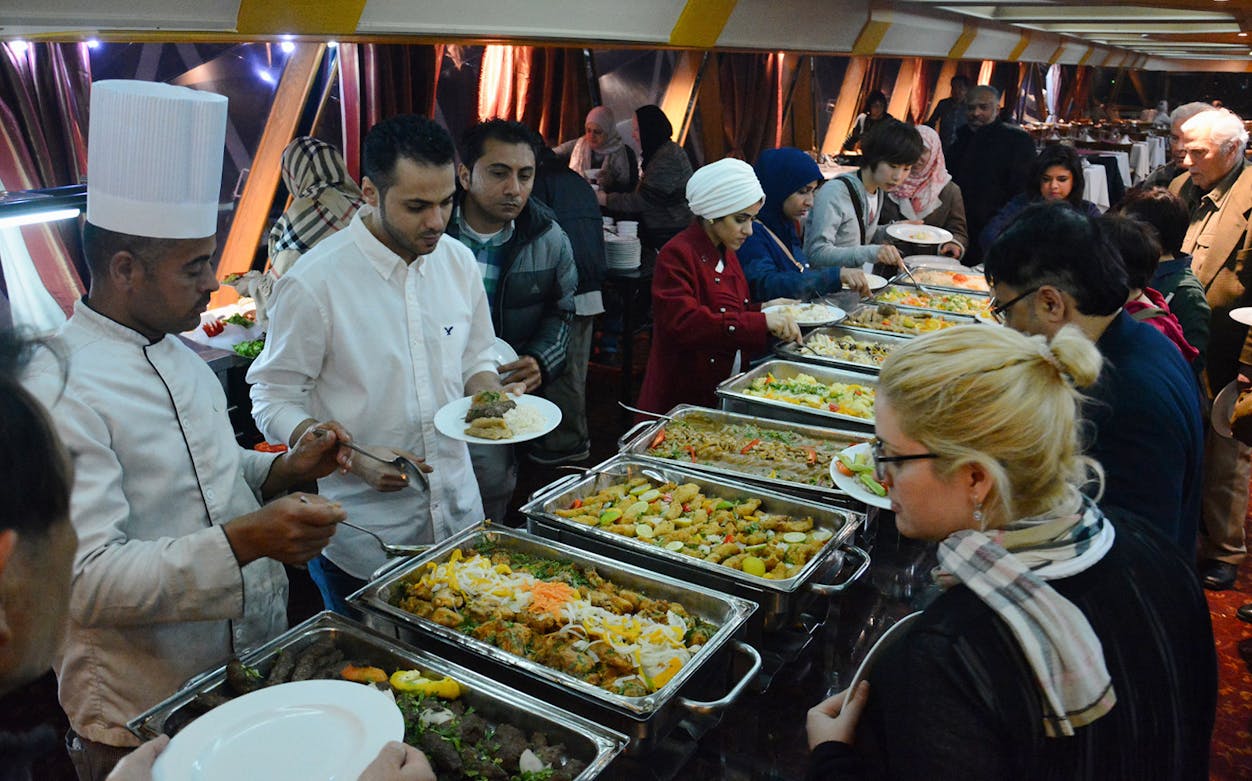 Guests enjoying a buffet on a Nile River dinner cruise with entertainment.