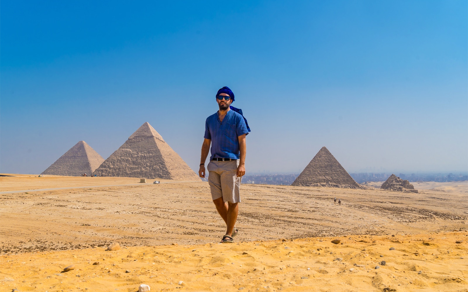 Man walking near the Pyramids of Giza, Egypt, under a clear blue sky.