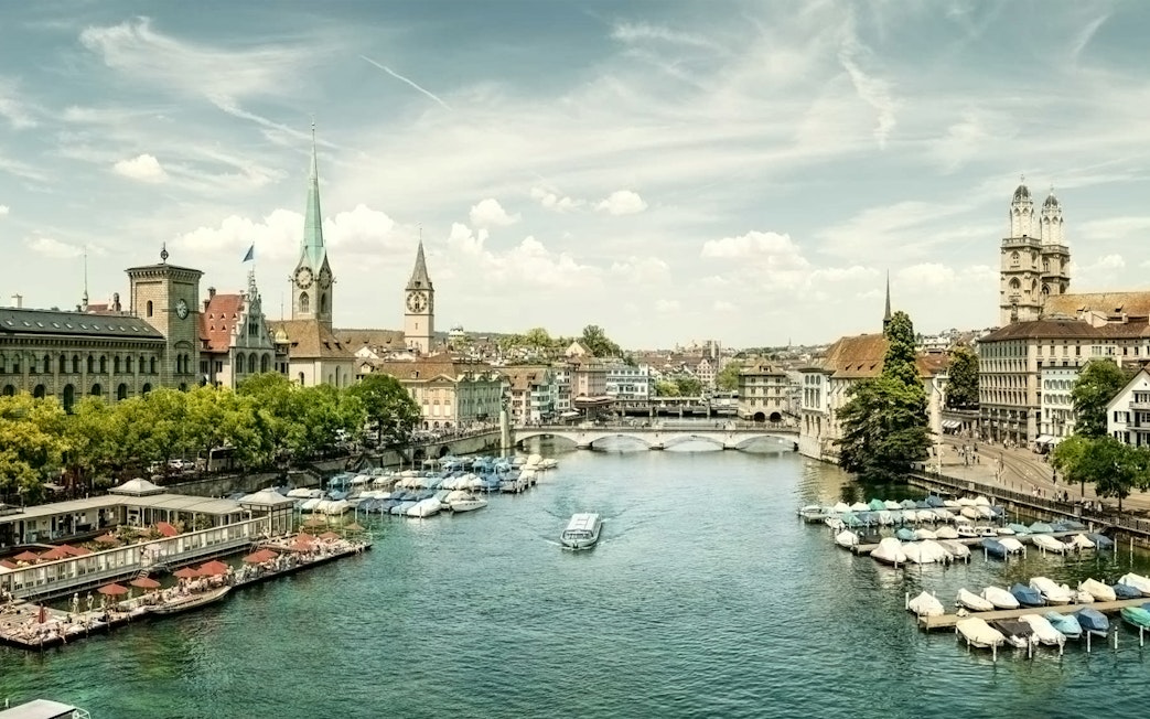 Zürich cityscape with Limmat River, historic buildings, and boats, part of a half-day tour including Lindt Home of Chocolate.