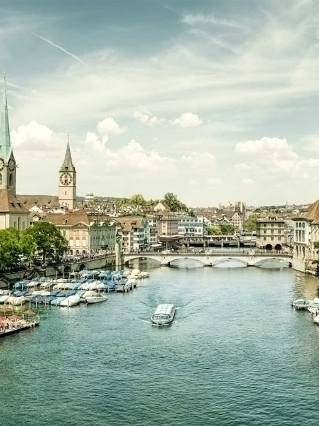 Zürich cityscape with Limmat River, historic buildings, and boats, part of a half-day tour including Lindt Home of Chocolate.