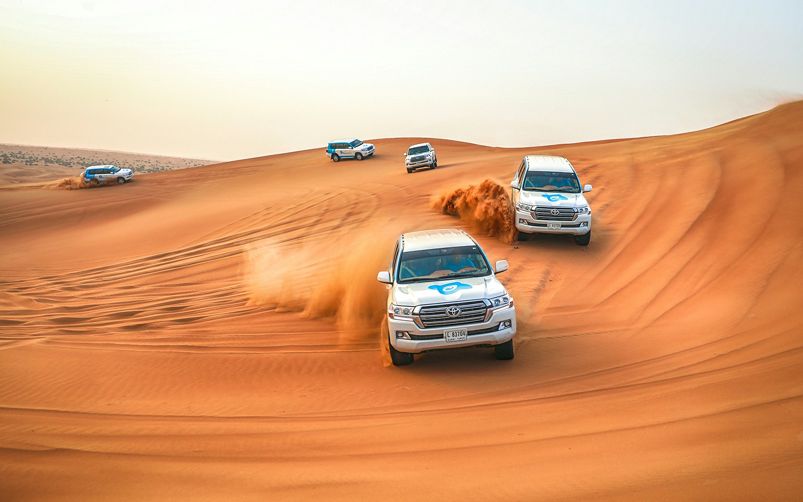 SUVs driving through desert dunes during a quad bike and dune bashing adventure.