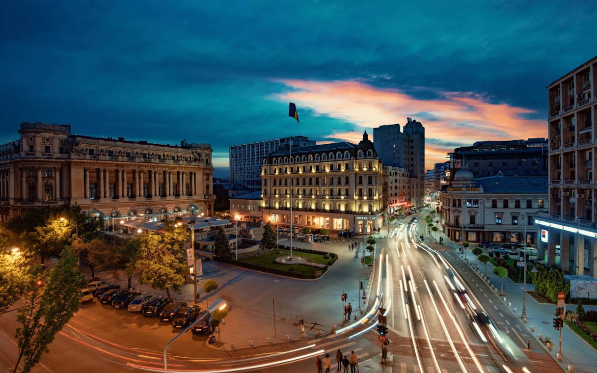 Cityscape at dusk with illuminated buildings and busy streets, After Dark City Tour.