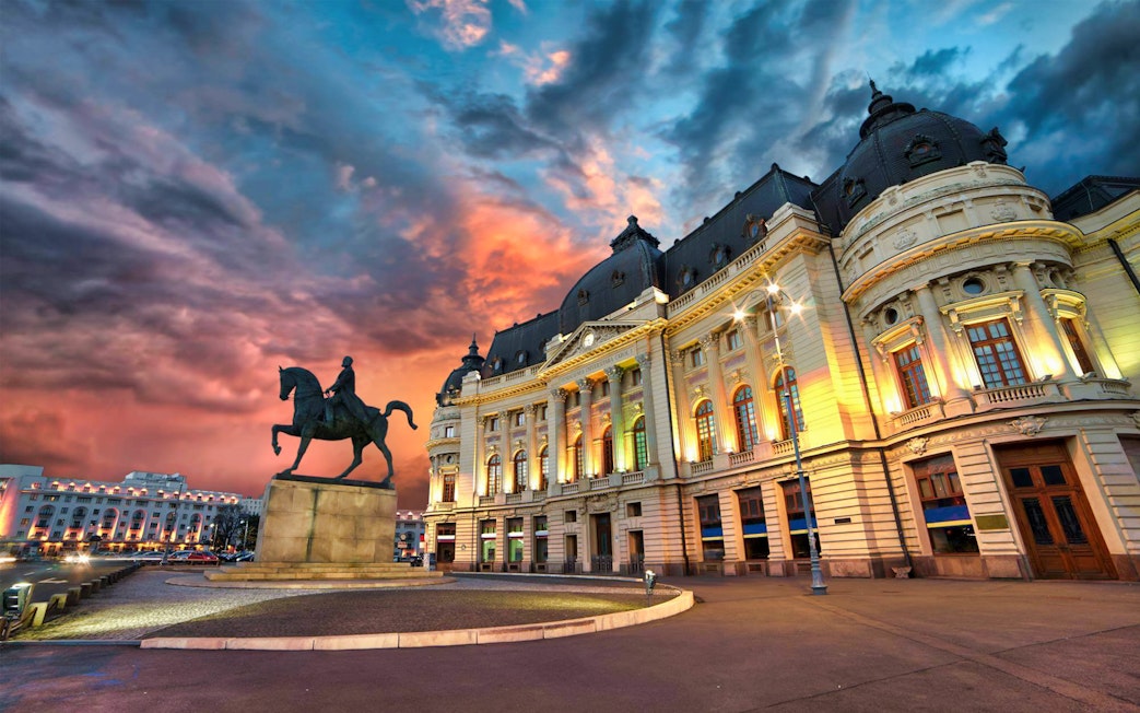 Equestrian statue and illuminated historic building at sunset on After Dark City Tour.