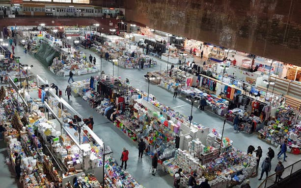 Indoor market in Bucharest with various stalls selling clothes, food, and household items.