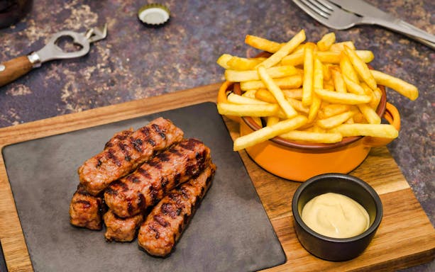 Grilled sausages and fries with mustard on Bucharest food tour.