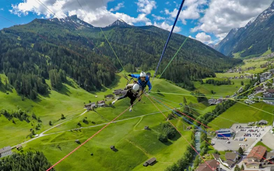 Tandem paragliding over green valleys and mountains in Tirol, Austria.