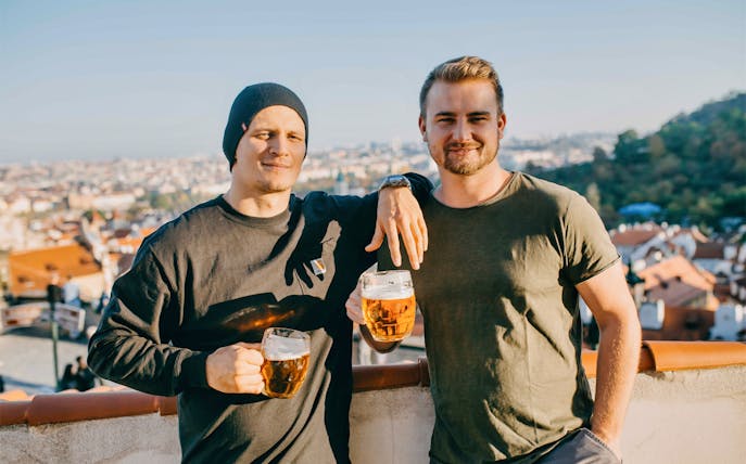 Two people enjoying beer with a view of Prague rooftops on the Castle Side tour.