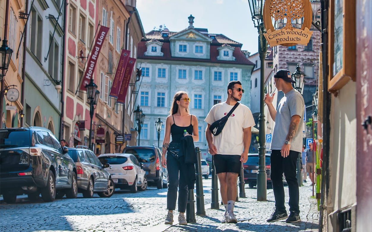 Tourists walking on a cobblestone street in Prague's historic district near the castle.