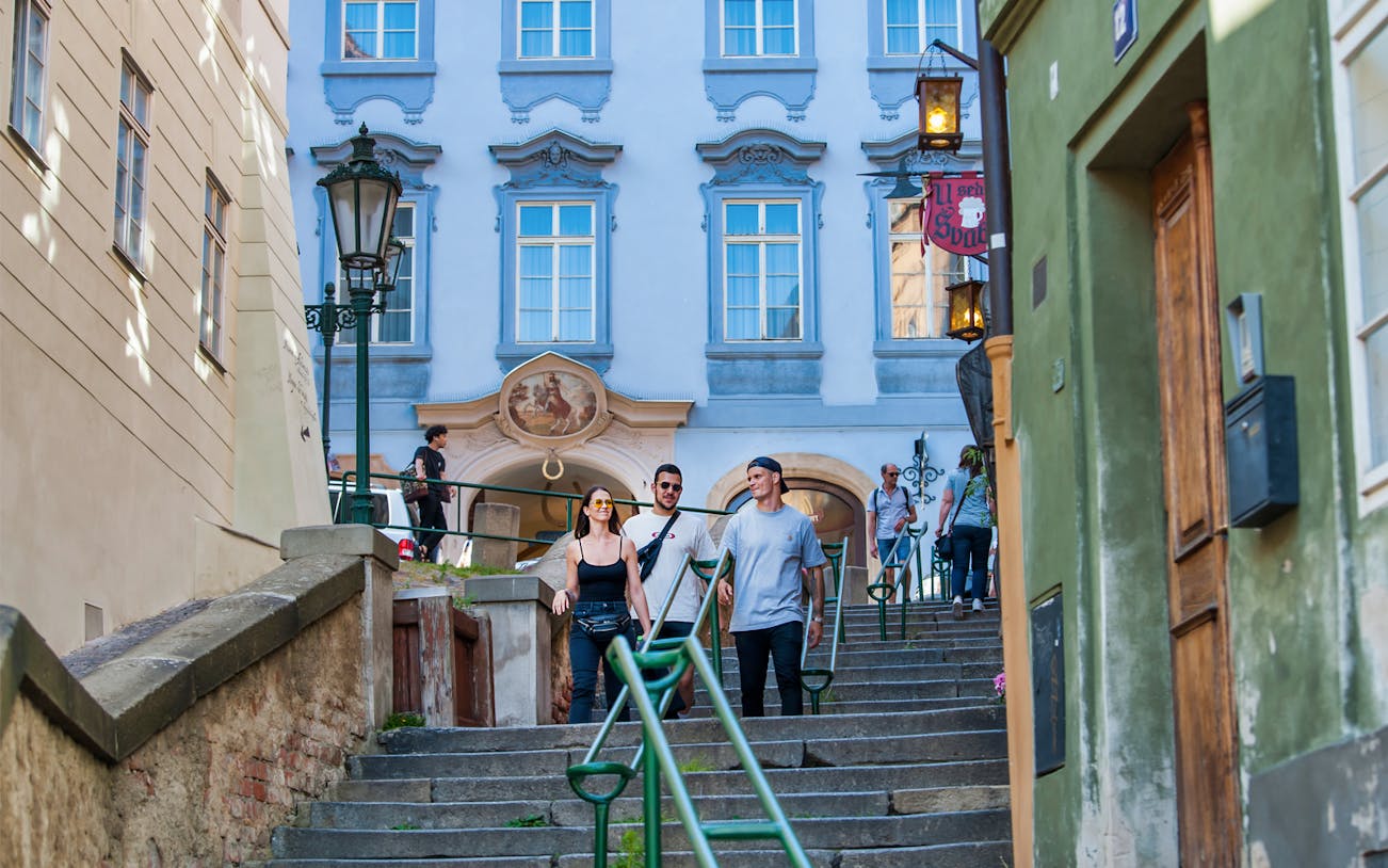Tourists walking down historic steps in Prague's Old Town.