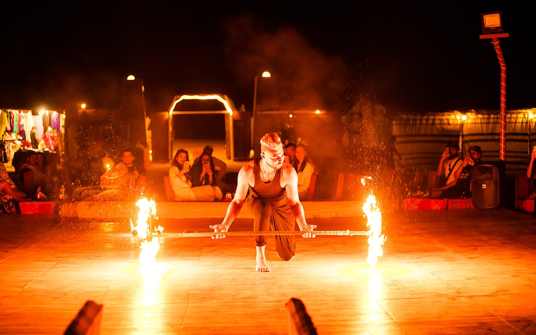 Fire performer at a desert safari in Dubai, entertaining guests with a flaming staff.