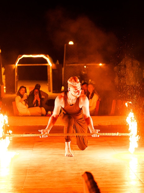 Fire performer at a desert safari in Dubai, entertaining guests with a flaming staff.