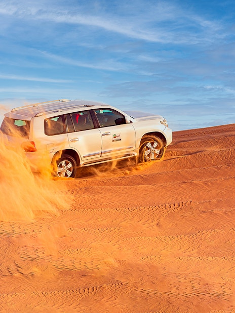 SUV driving through Dubai desert dunes on a safari adventure.