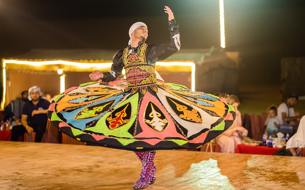 Dancer performing traditional Tanoura dance in Dubai desert camp.