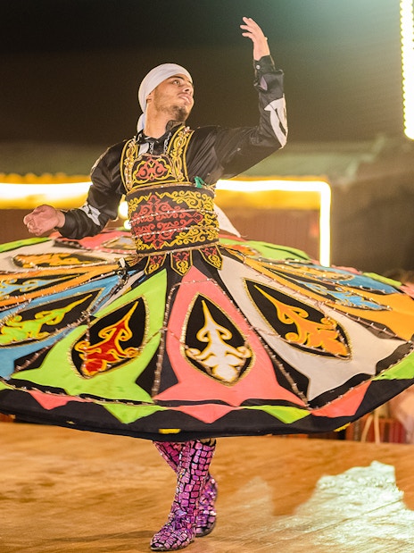 Dancer performing traditional Tanoura dance in Dubai desert camp.