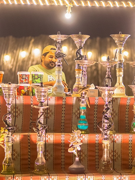 Hookah display at a desert safari in Dubai, featuring various flavors and a vendor.