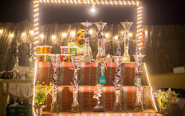 Hookah display at a desert safari in Dubai, featuring various flavors and a vendor.