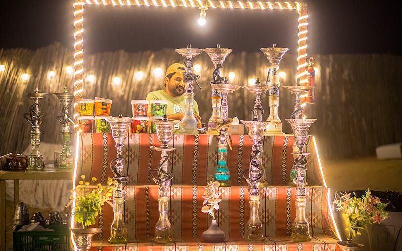 Hookah display at a desert safari in Dubai, featuring various flavors and a vendor.