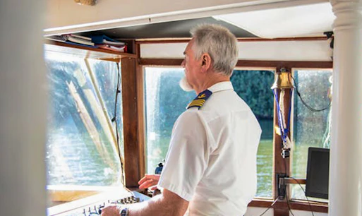 Captain steering boat on Tweed River rainforest lunch cruise.